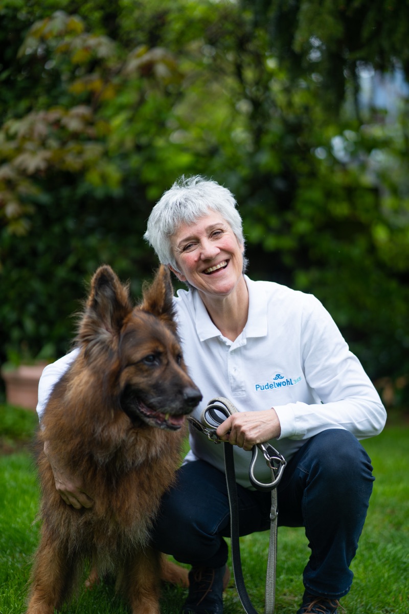 Angela, Geschäftsführerin von Pudelwohl365, mit ihrem Schäferhund im Garten